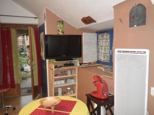 ein Wohnzimmer mit einem Flachbild-TV und einem Tisch in der Unterkunft Mas de La Boheme - L'Hermet in Saint-Léons