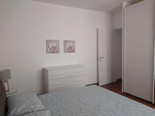 um quarto branco com uma cama e uma cómoda em Beach House em Piombino