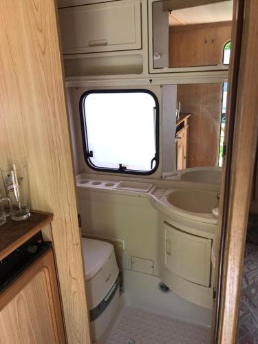a small bathroom with a sink and a window in an rv at Przyczepy Kemping Polaris Półwysep Helski in Chałupy