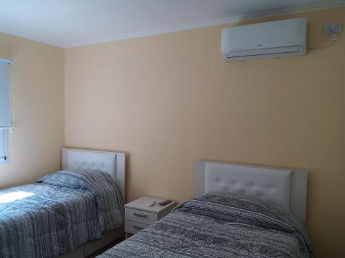 a bedroom with two beds and a air conditioner on the wall at Melo 2203 Duplex 1 in Belén de Escobar