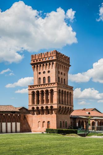 a building with a tower in the middle of a field at Albergo dell'Agenzia in Bra