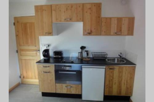 une cuisine avec un comptoir noir et des placards en bois dans l'établissement Loue studio de vacances rénové à Névache, à Névache