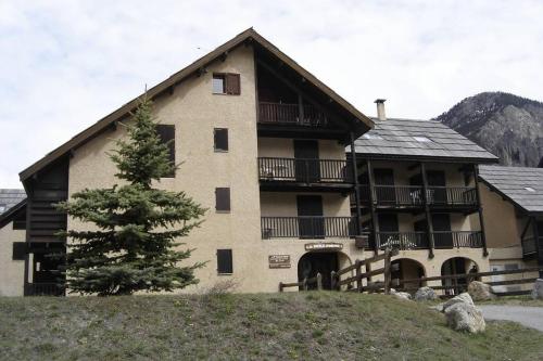 une grande maison avec un pin en face dans l'établissement Loue studio de vacances rénové à Névache, à Névache