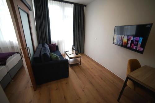a living room with a couch and a flat screen tv at DIWOTEL by Trip Inn Frankfurt Airport Dreieich in Dreieich