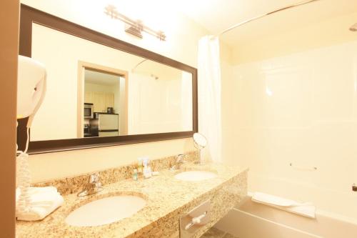 a bathroom with two sinks and a large mirror at Vegreville Suites in Vegreville