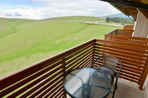 a table and chairs on a balcony with a view of a field at The View Zlatibor Hills in Zlatibor