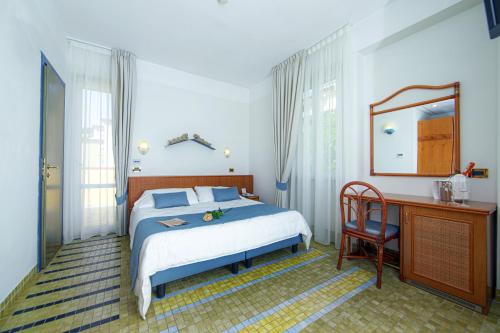 a bedroom with a bed and a desk and a mirror at Hotel Della Baia in Portovenere