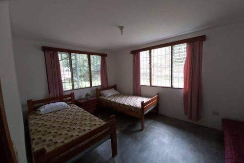 a bedroom with two beds and two windows at The Calm House in Turrialba