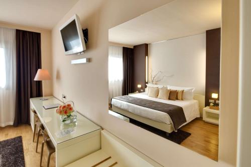 a hotel room with a bed and a desk and a mirror at Best Western Plus Leone di Messapia Hotel & Conference in Lecce