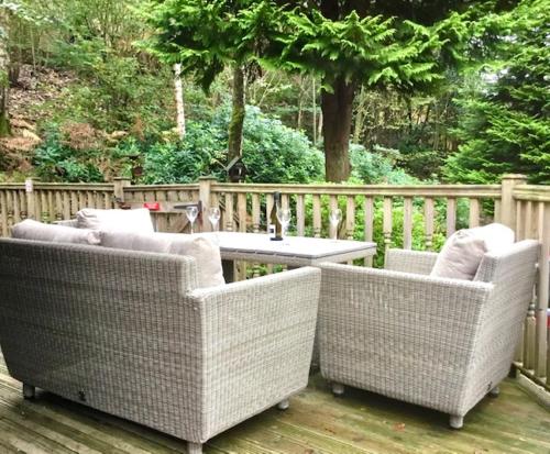 two wicker chairs and a table on a deck at Mistletoe One Luxury Lodge with Hot Tub Windermere in Windermere
