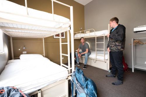 two men standing in a room with bunk beds at YHA Melbourne Central in Melbourne