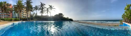 a large blue swimming pool next to a beach at Cimarron Suites Playa Parguito in Aricagua