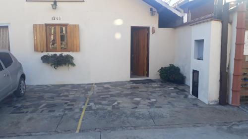 a building with a door and a car parked in a parking lot at Casa Moreira´s Chalés in Monte Verde