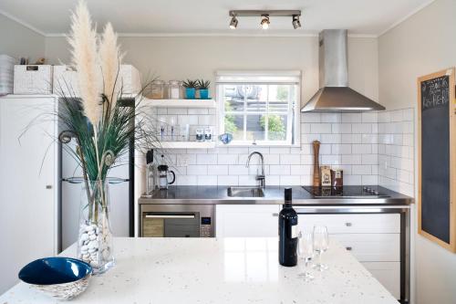 a kitchen with a table with a bottle of wine at Black Bach on Burrell in Oneroa