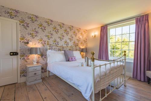 a bedroom with a bed and a window with purple curtains at Hill House Farm by Bloom Stays in Canterbury