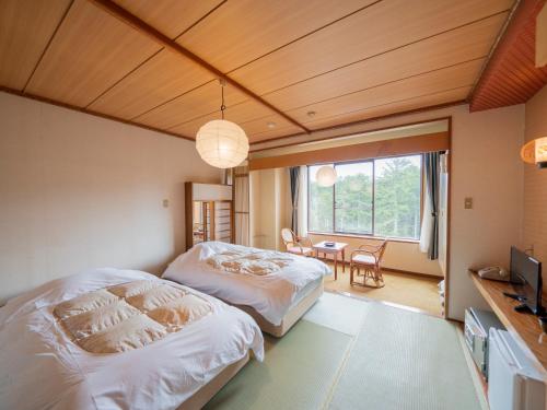 1 dormitorio con 2 camas, mesa y ventana en Kawayu Kanko Hotel, en Teshikaga