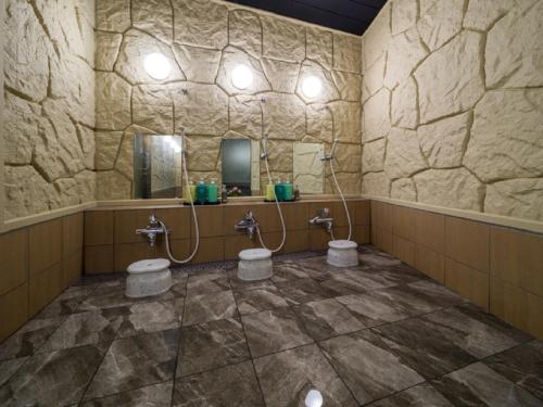 a stone bathroom with two toilets and a mirror at Hotel Route-Inn Komoro in Komoro