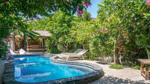a swimming pool in a garden with trees and flowers at Giliranta in Gili Trawangan