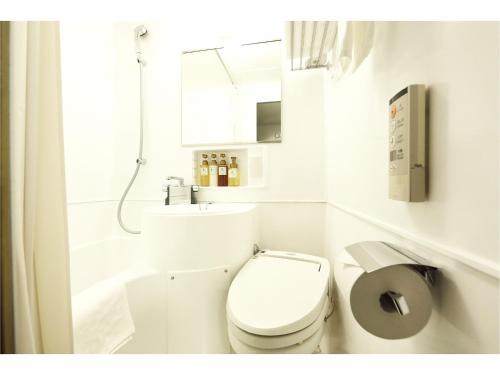 a white bathroom with a toilet and a sink at Sendai Business Hotel Ekimae in Sendai