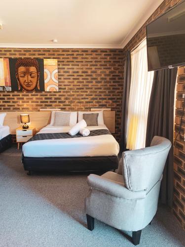 a bedroom with a king sized bed and a chair at Squatters Homestead Motel in Casino