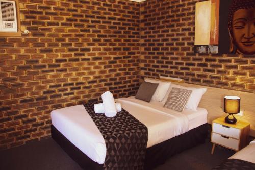 a bedroom with a bed and a brick wall at Squatters Homestead Motel in Casino