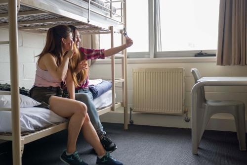 two girls sitting on a bed in a bedroom at Melbourne Metro YHA in Melbourne