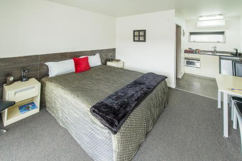 a bedroom with a large bed and a kitchen at 151 On London Motel & Conference Centre in Whanganui