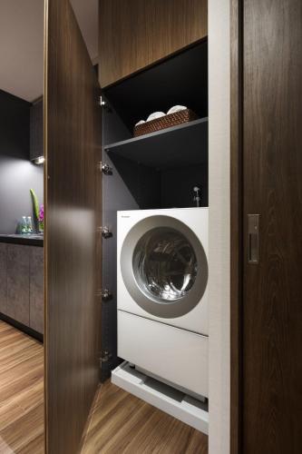 a laundry room with a washing machine in a closet at Hiyori Ocean Resort Okinawa in Onna