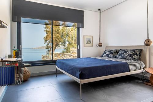 a bedroom with a bed and a large window at Blue Frames Summer House in Andros