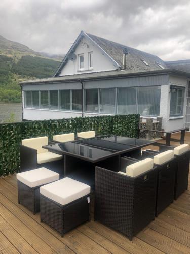 a deck with chairs and tables and a building at Amazing Alps and Loch views - HOT TUB and pet friendly in Arrochar