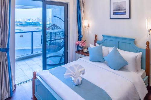 a bedroom with a blue and white bed and a balcony at Haikou Bay Hengda Yige Holiday Condo Hotel in Haikou