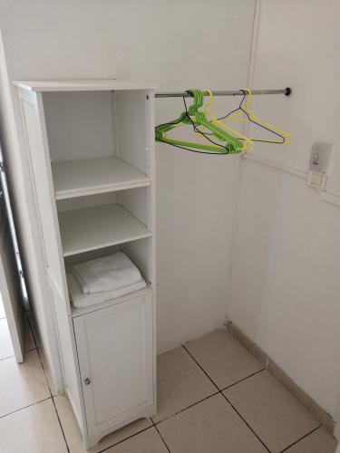 a small white closet with a white shelf and greenabling at Zoiseaux Paradis in Ravine des Cabris