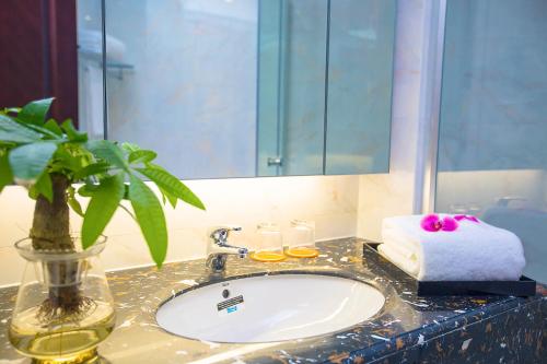 a bathroom counter with a sink and a mirror at Haikou Bay Hengda Yige Holiday Condo Hotel in Haikou