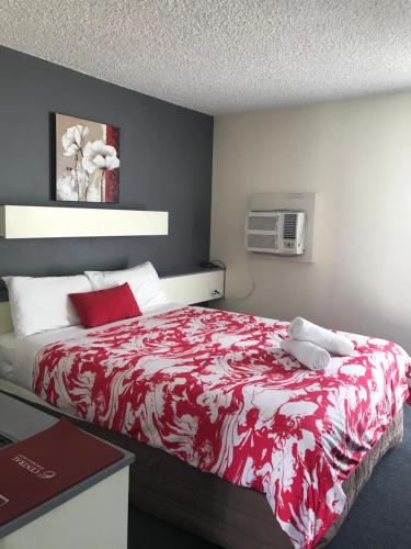 a bedroom with a bed with a red and white blanket at Emerald Central Hotel Official in Emerald