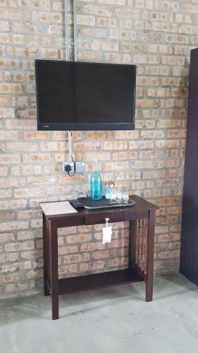 a wooden table with a television on a brick wall at Dungun Escapade Resort in Dungun