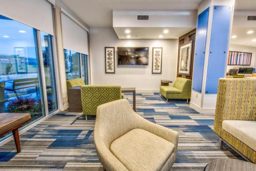 a waiting room with chairs and tables and windows at Holiday Inn Express & Suites Dallas NW - Farmers Branch by IHG in Farmers Branch