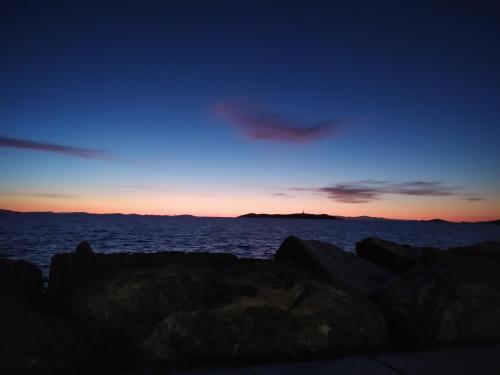 a sunset over the ocean with rocks in the foreground at Nisaki Hotel & Elite Suites in Ermoupoli