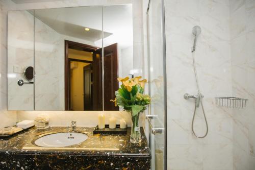 a bathroom with a sink and a shower with a mirror at Haikou Bay Hengda Yige Holiday Condo Hotel in Haikou