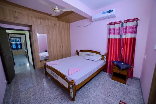 a small bedroom with a bed and a red curtain at TrueLife Homestays - Royal Nagar -Near Railway Station on way to Balaji Temple - Best Location - Mountain View - Fully Furnished 2BHK AC Apartments for Family Stay - Modular Kitchen, Fast WiFi, Android TV - 250 Jio Channels - Top Service with lots of Love in Tirupati