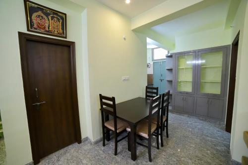 a dining room with a table and chairs and a door at TrueLife - Railway station - On way to Balaji Temple - Breakfast included - Large 2BHK AC Apartments - Enjoy morning Coffee Tea Milk - Modular Kitchen - Fast WiFi, Jio Smart TV - Easy access to all Temples - Travels - TrueLife's service with lots of Love in Tirupati
