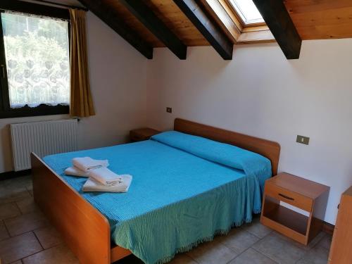 una camera da letto con un letto con lenzuola blu e una finestra di Al Fogolar a Villa Santina