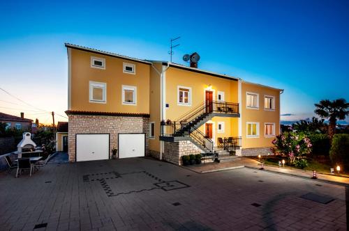 a yellow house with a large courtyard in front of it at Apartments Euphemia in Rovinj