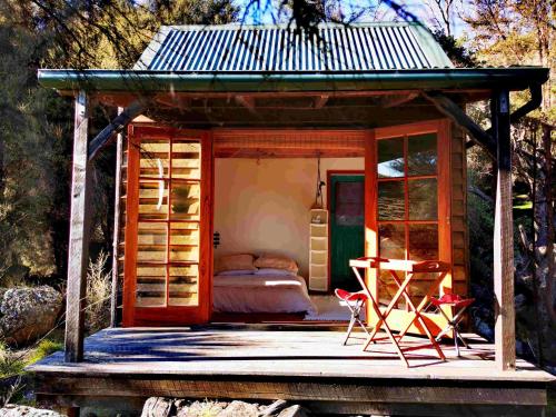 a small room with a bed and a table and chairs at Manaaki Mai, Rustic Retreat Bush Cabin in Christchurch