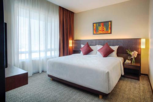 1 dormitorio con 1 cama blanca grande con almohadas rojas en Furama Bukit Bintang, Kuala Lumpur, en Kuala Lumpur