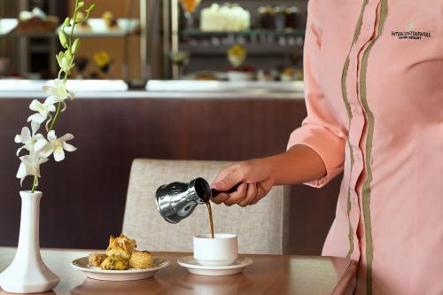 a woman pouring coffee into a cup on a table at InterContinental Aqaba by IHG in Aqaba