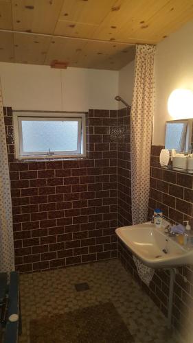 a bathroom with a sink and a brick wall at Hummingen Strand 21 in Dannemare