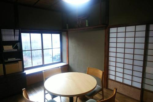 a dining room with a table and chairs and windows at まるまる貸切一軒家 ゆっくり過ごせる民泊 武甲ステイ in Yokoze