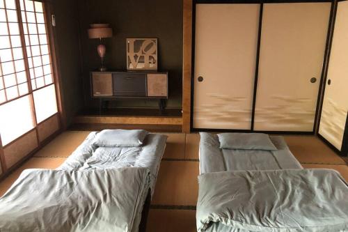 Habitación con 2 camas, mesa y ventanas. en まるまる貸切一軒家 ゆっくり過ごせる民泊 武甲ステイ, en Yokoze