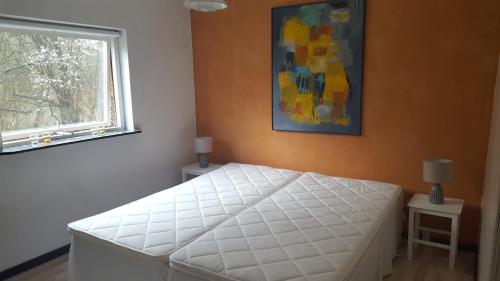 1 dormitorio con cama blanca y ventana en Hummingen Strand 21, en Dannemare
