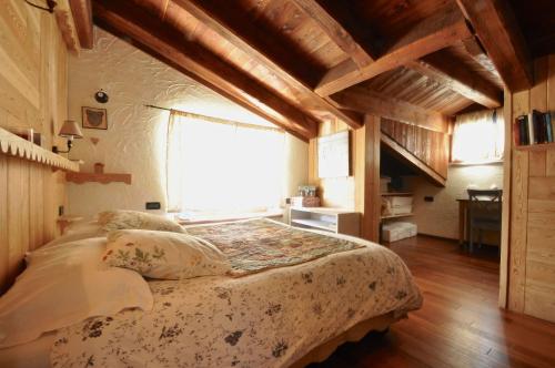 - une chambre avec un lit dans une pièce dotée de plafonds en bois dans l'établissement Appartamento Collomb Ruitor, à La Thuile